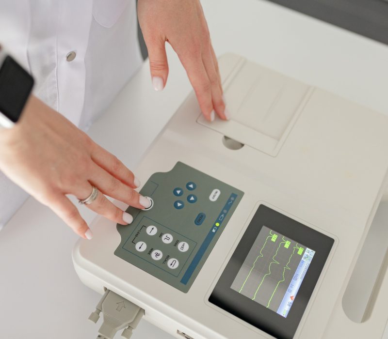 Woman cardiologist doctor makes electrocardiography procedure using cardiograph in modern clinic. Test, professional consult, diagnostic, healthcare, medical service.